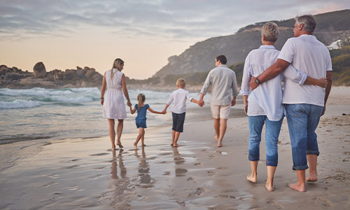 generations of family walking down beach