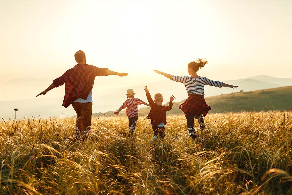 family dancing in the grass at sunset